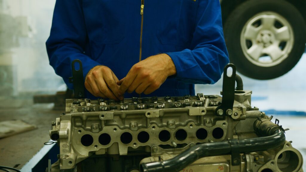 cropped-torso-of-man-in-blue-coveralls-working-on-engine-block