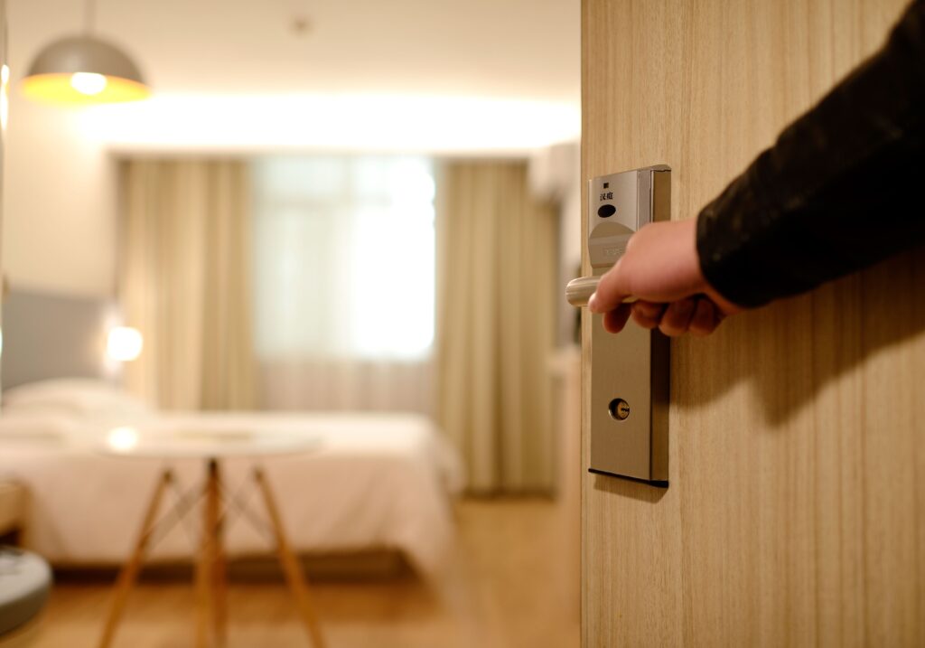 hand-opening-hotel-room-door-bed-window-in-view