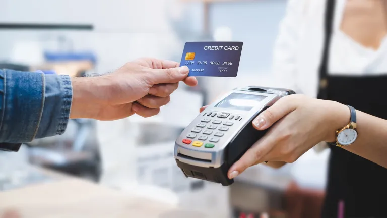 hand-holding-credit-card-over-cc-processing-machine-being-held-by-another-person